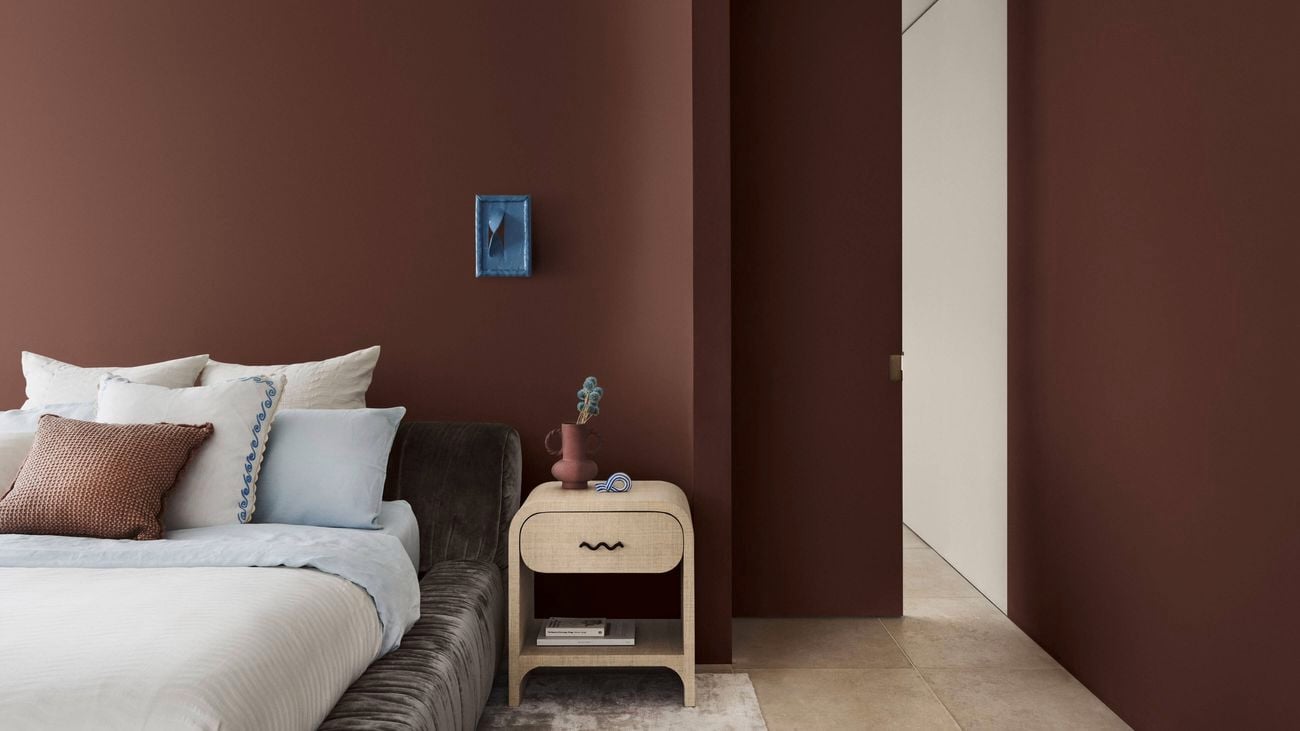 A bedroom with brown walls, a bed and a side table in it.