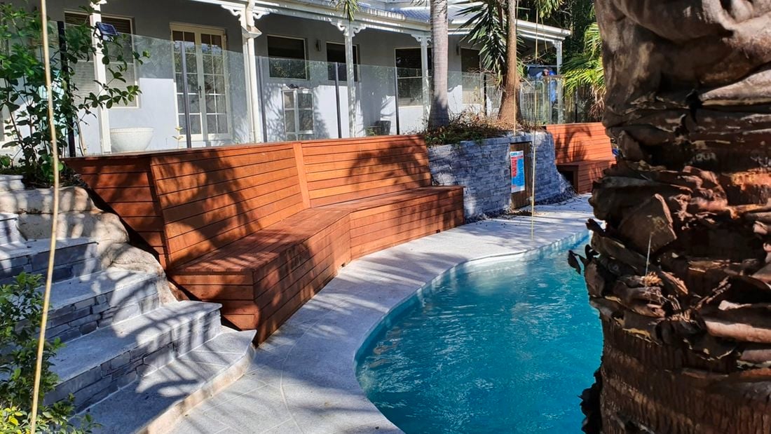 Brown timber built-in bench seating around a pool area is a perfect outdoor decking solution.
