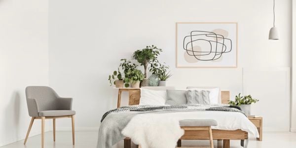 Modern bedroom with wooden bed, neutral bedding, and indoor plants.