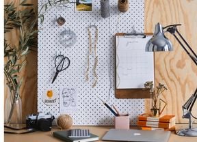 Desk with laptop, lamp and items arranged on a peg board