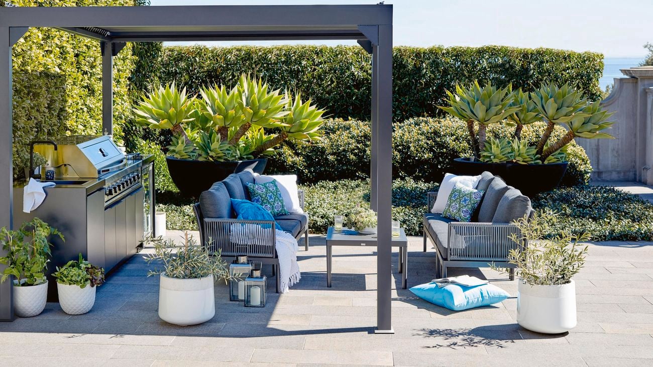 Covered outdoor kitchen and outdoor furniture in a coastal garden setting