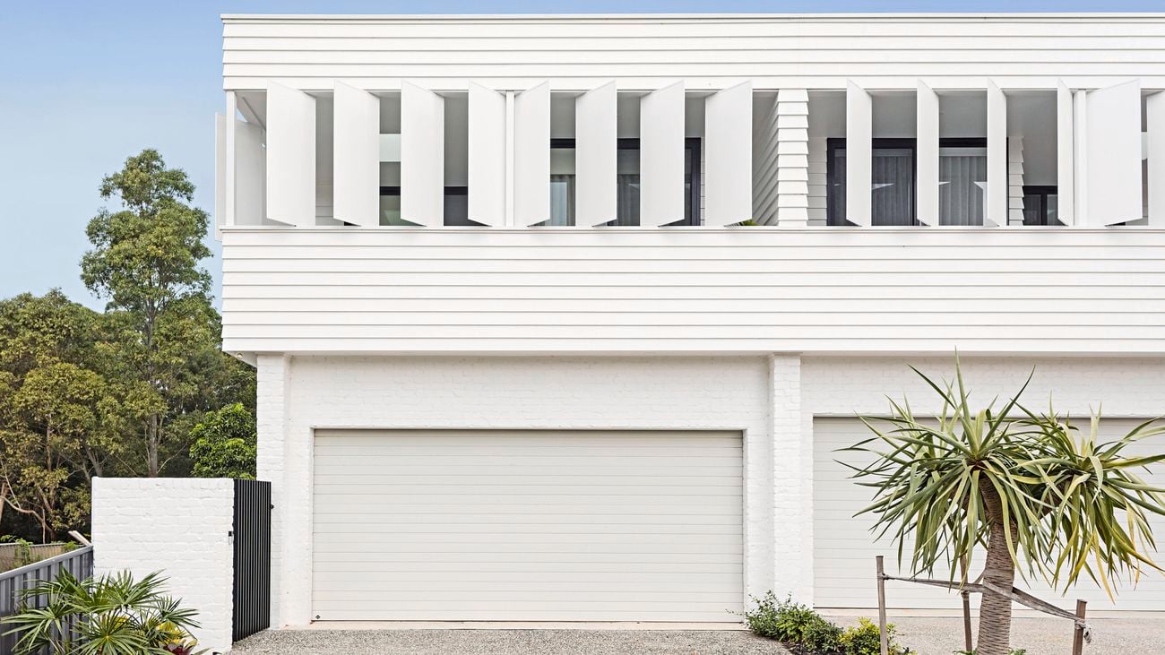 Front exterior of a modern coastal two-storey house with a shaded balcony.