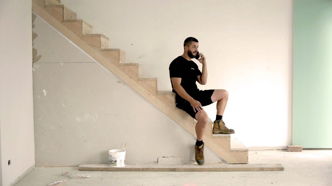 A tradie on a job site on his phone.