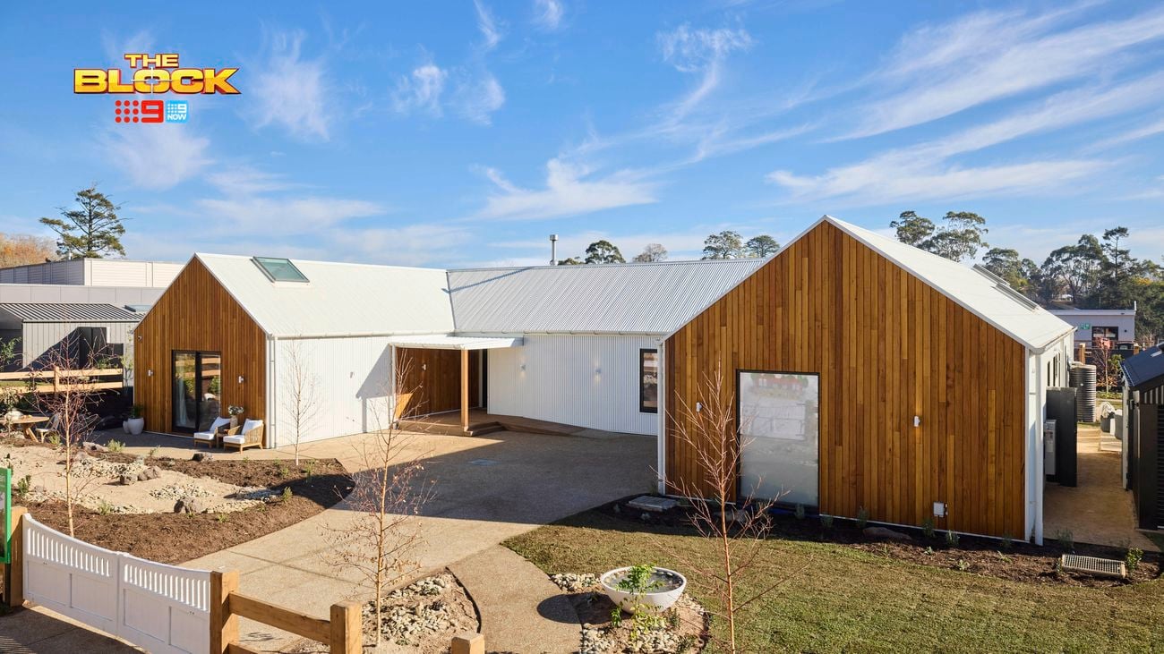 The front area of a house with a timber fence, grassed area, trees and a driveway in it.