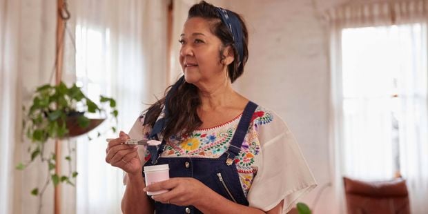 Linda standing in a painted room with a sample pot and brush in her hands