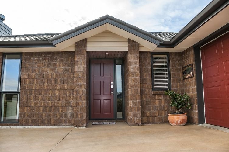 Exterior of a townhouse with dark brown bricks and a dark red front door
