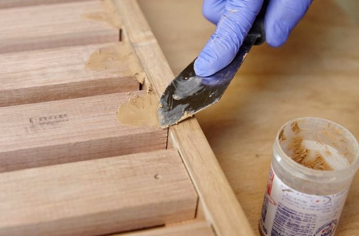 Person using putty to fill cracks in timber joins