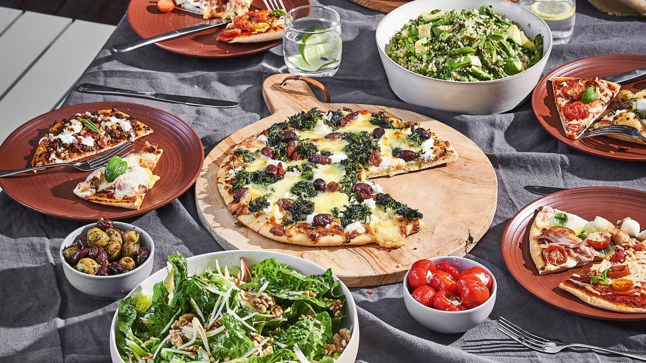 A pizza fresh out of a Bunnings pizza oven sitting on a table with sides.
