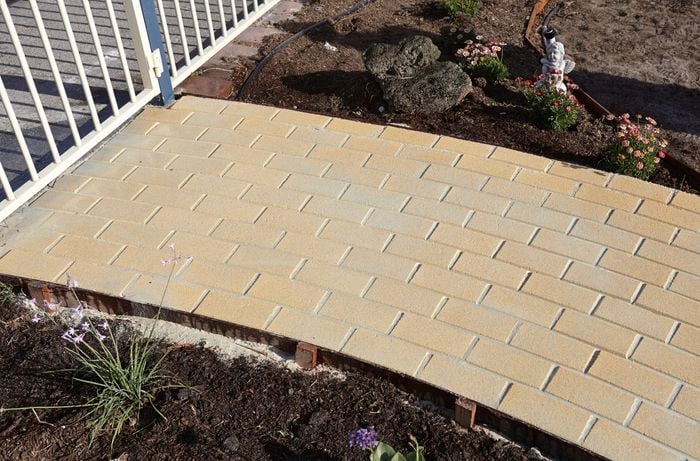 A finished curved pathway with pale yellow pavers
