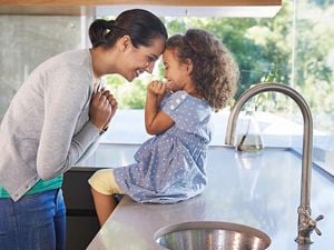 Mother and her daughter sit in the kitchen.