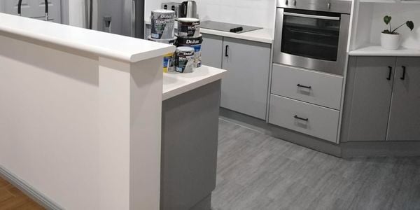 Kitchen with grey cabinets and white benchtops.