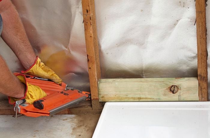 Nogs being fitted to the inside of a wall frame and nailed down with a nail gun