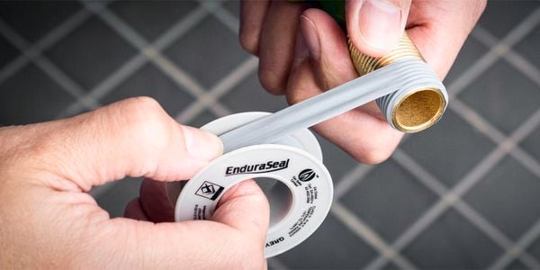 A person applying thread seal tape.