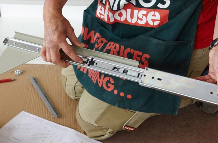 A person separating the side brackets from a drawer runner 