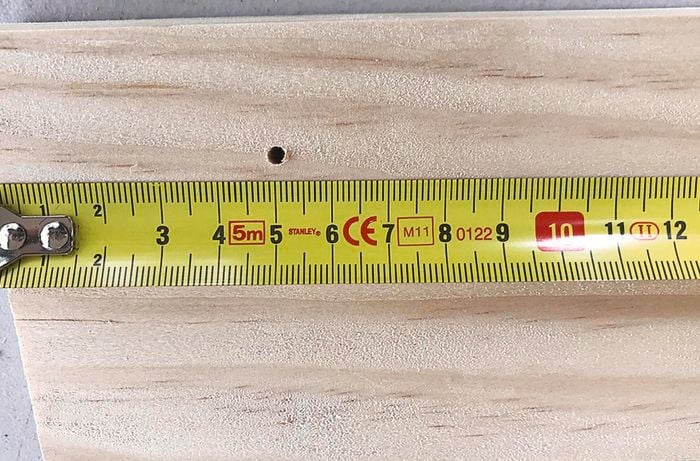 Holes being drilled into a backing board for a coat rack