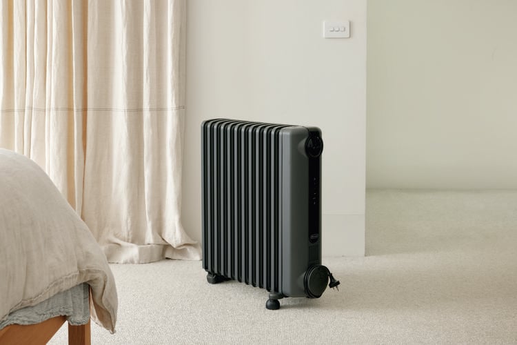 A room with carpet on the floor, a bed and a heater in it