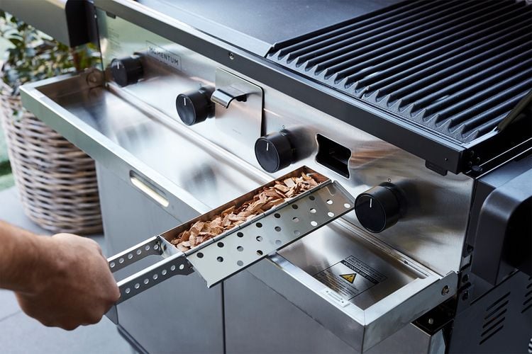 Woodchips being added to a barbecue for the purpose of smoking meat