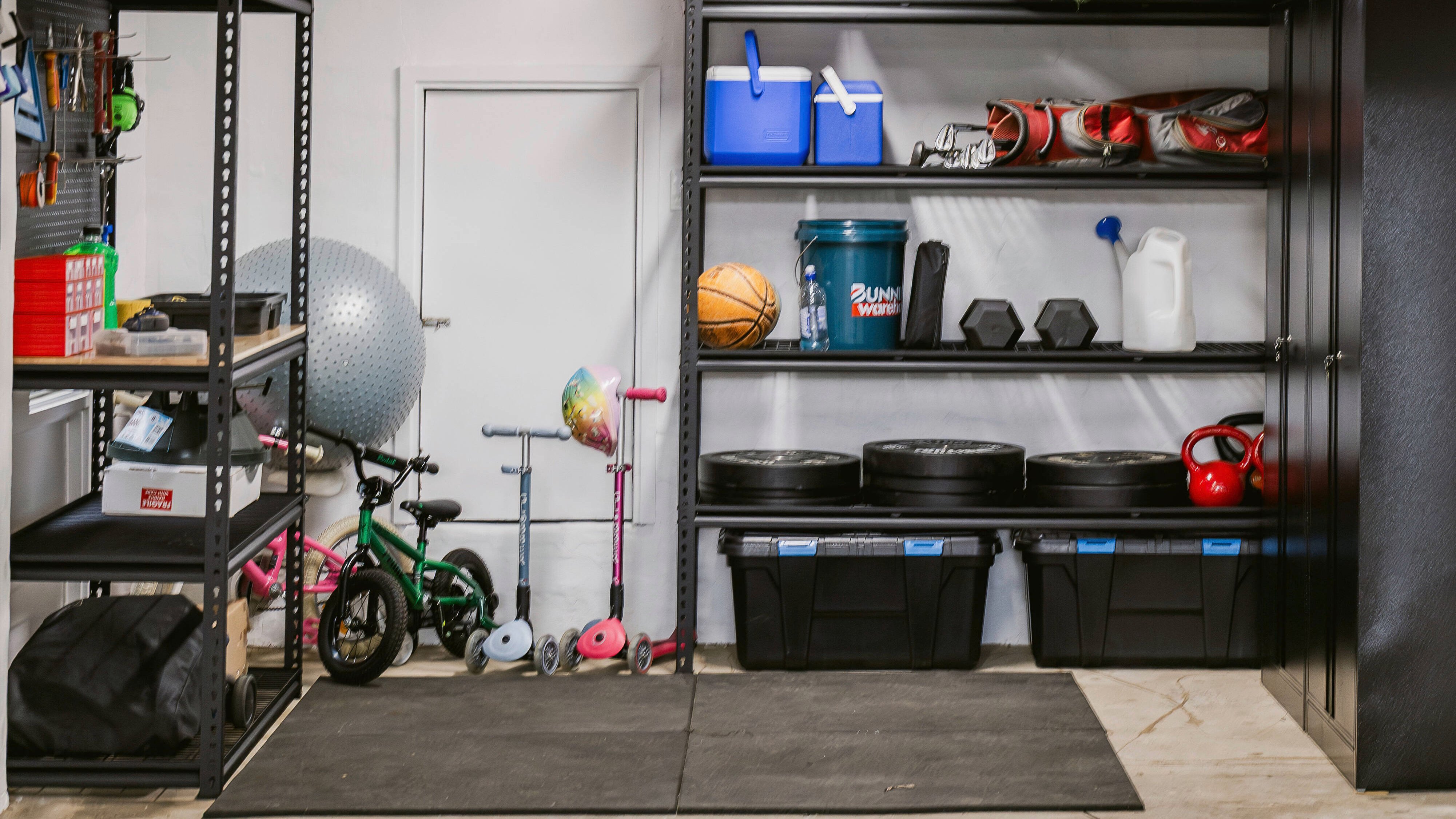 After view of an organised garage with shelves, storage tubs and neatly arranged equipment.