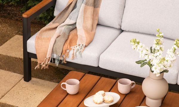 Outdoor timber setting on a paved area with a hedge behind it.