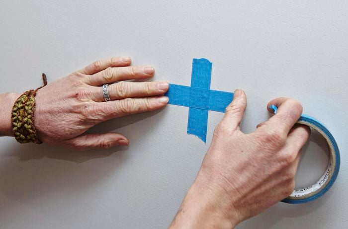 A person marking a wall with masking tape