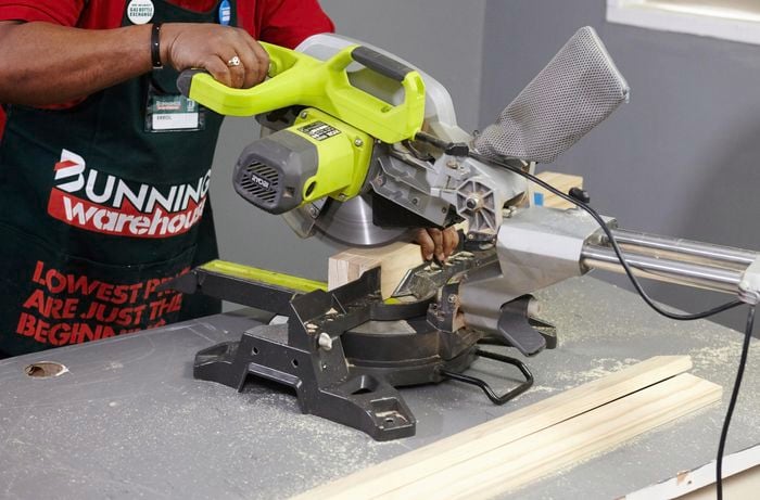 A person cutting pine timber with a drop saw