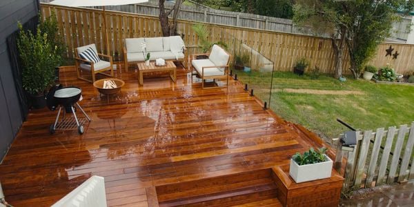 Back garden with timber decking showcasing glass fencing and lounge