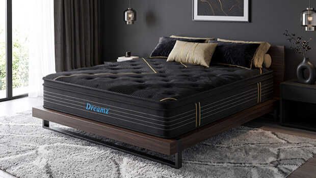 A black mattress sitting on a bedframe in the middle of a bedroom with a dark feature wall and dark bedside tables and ornaments.