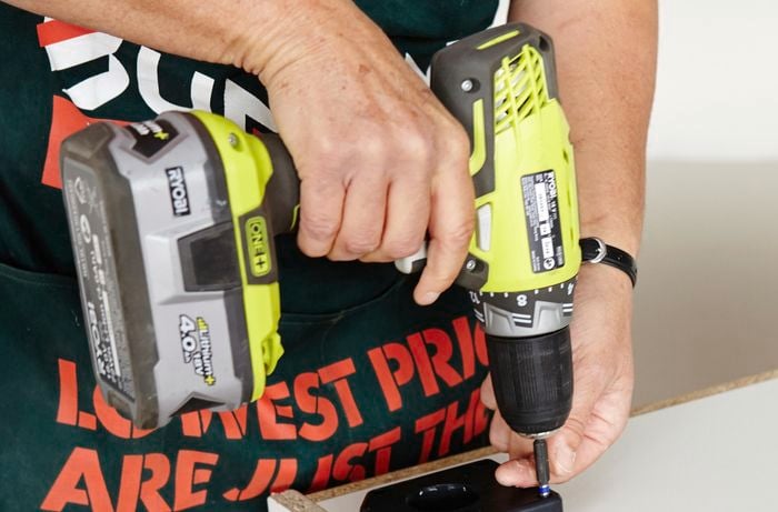 Person drilling screw into foot plates
