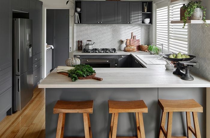 Modern kitchen with dark grey cabinets and silver appliances, timber floor and fresh produce on the benchtop
