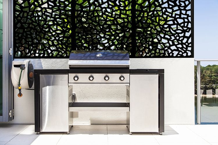 Backyard 4-burner barbecue in front of decorative screening