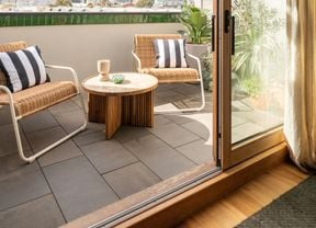 A cozy outdoor corner with wicker chairs, colorful cushions, and various potted plants creating a relaxing, nature-inspired ambiance.