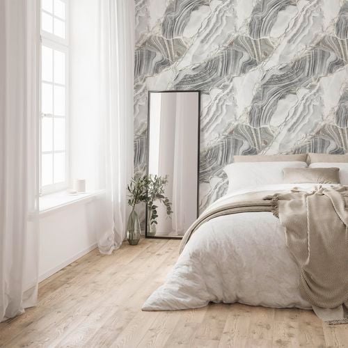 A white furnished bedroom with marble look wallpaper.