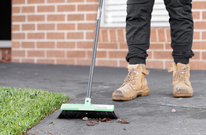 A person sweeping the driveway with a broom
