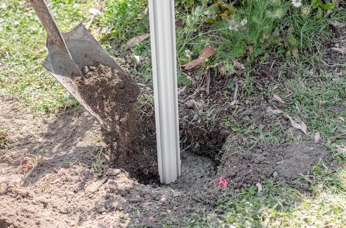Filling the letterbox post hole with soil using a spade