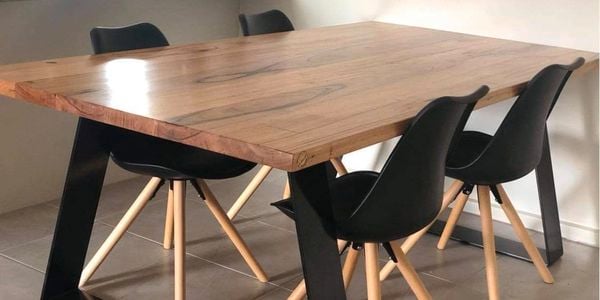 Timber table in a living room surrounded by dining chairs