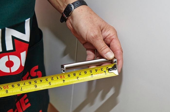 Person measuring cupboard doors for door handle location