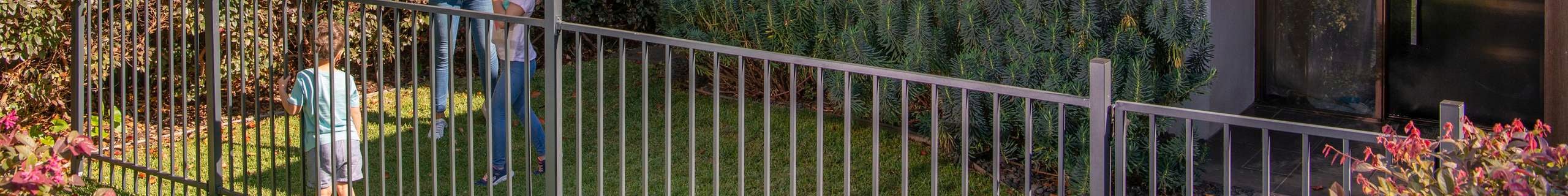 A woman playing a game with kids behind fencing in a backyard.