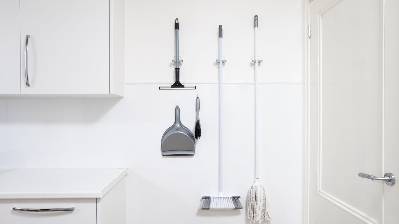 Hooks and broom grippers are used to hang cleaning tools in a laundry