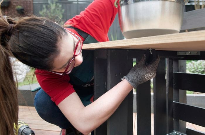 A screw being added to the bottom of a table surface for a kids play kitchen