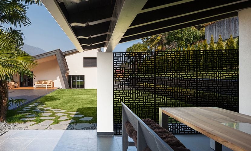 Covered outdoor area with dining table and decorative screens