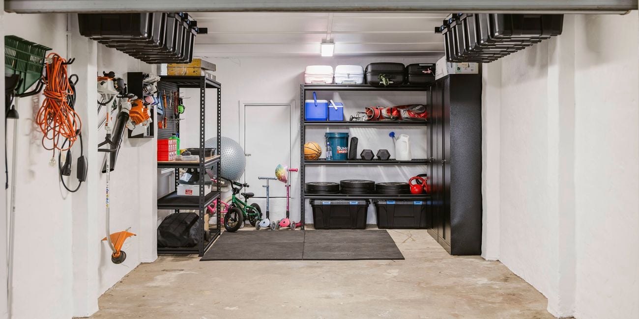 Completed garage makeover with organised shelves, ceiling storage tubs and wall-mounted tools.
