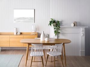 Dining room with white panelled walls, timber dining table and fireplace.