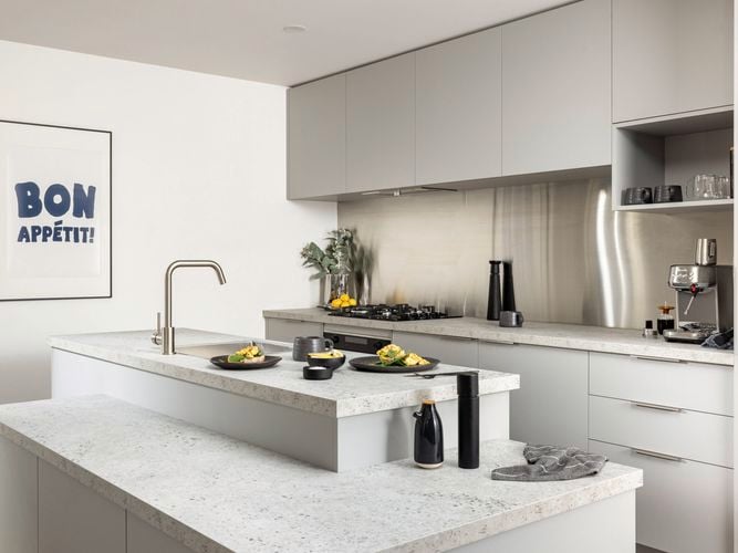 Light grey modern kitchen with a marble benchtop, black crockery and a coffee machine on the bench.