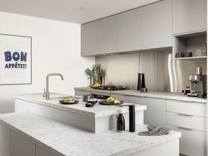 Light grey modern kitchen with a marble benchtop, black crockery and a coffee machine on the bench.