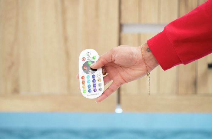 A person is using a remote control to adjust bathroom LED strip light settings