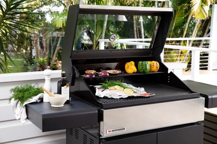 4-burner barbecue in backyard with fish and vegetables roasting