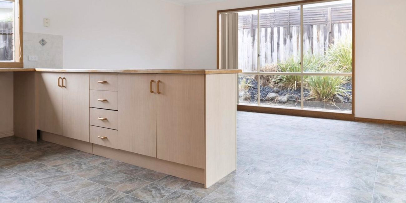 Old and dated kitchen interior, including kitchen bench and cabinets.