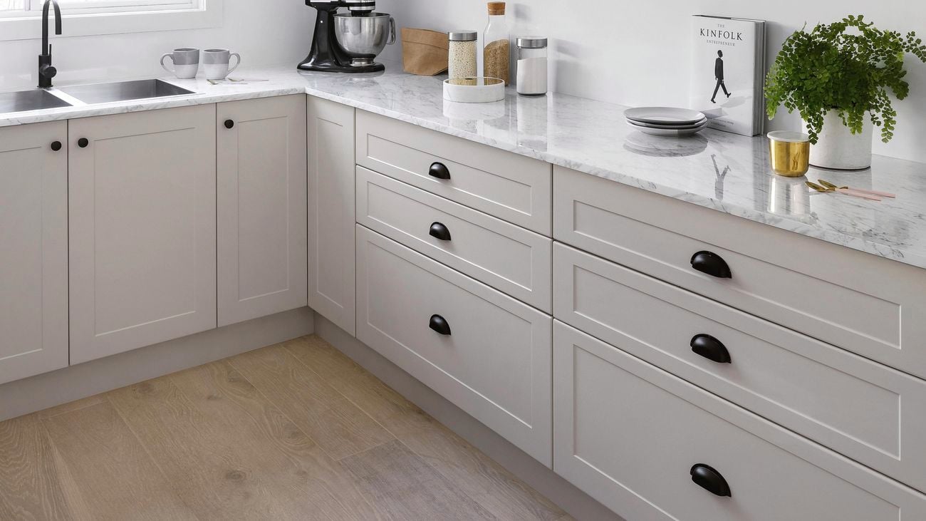 Black tap, sink and white cupboards with black handles in a kitchen space.