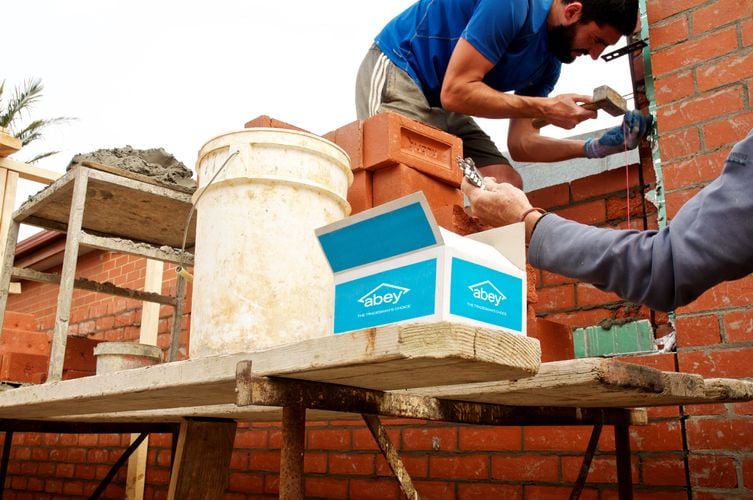 Bricklayer using mallet while laying bricks