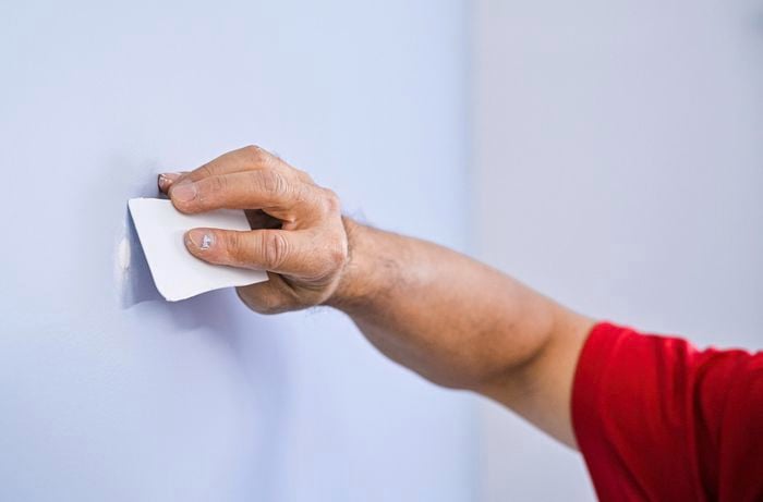 A person holding a scraper next to a wall